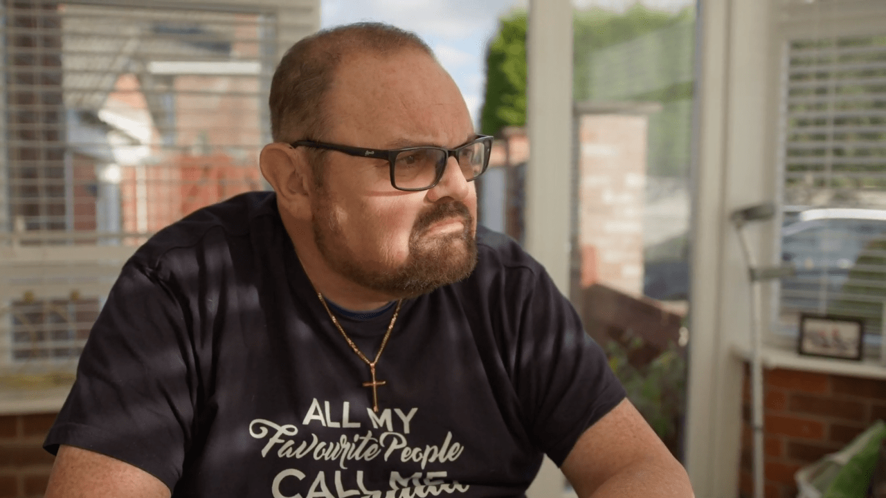 Portrait of Mike, a middle-aged man wearing glasses and a blue shirt, looking out of the window and contemplating his future,